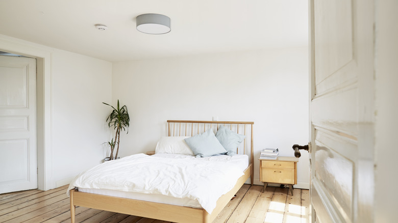 A white bedroom scheme with a wooden bed in the middle.