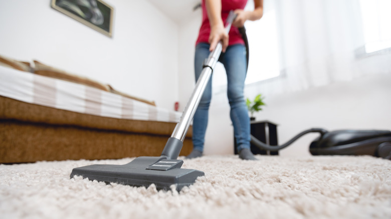 woman vacuuming bedroom carpet