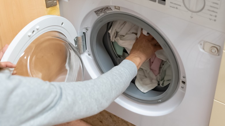 Person loading clothes into washer