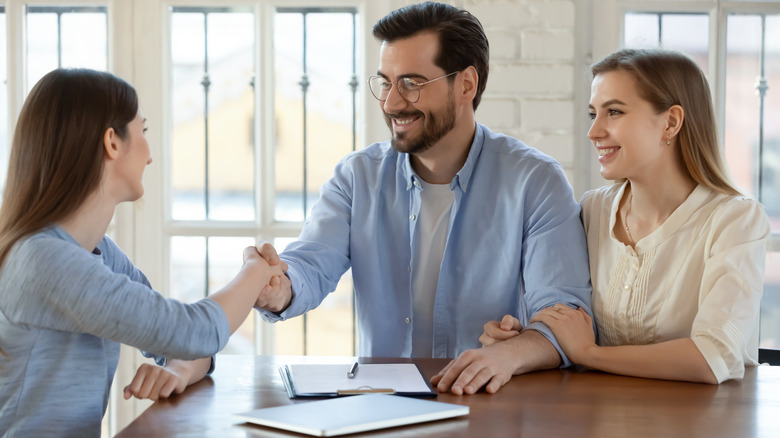 couple shaking hands with woman