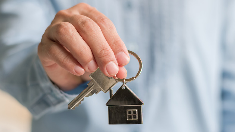 man holding key with house keychain