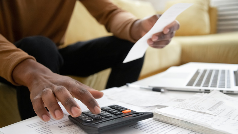 man calculating taxes on calculator 