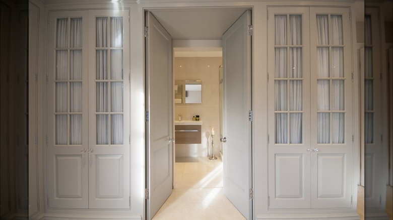 Two closets with glass paneled, white French doors