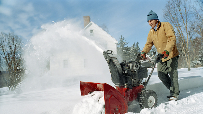 A person using a snow blower in front of their home