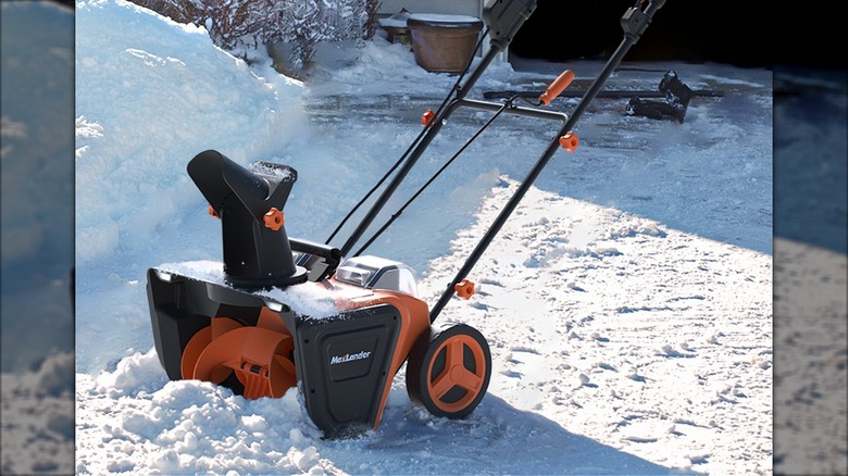 The Maxlander Snow Blower next to a pile of snow and in front of a mostly cleared driveway