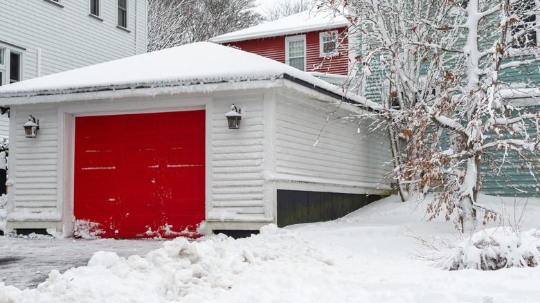 White garage with bright red door covered in snow