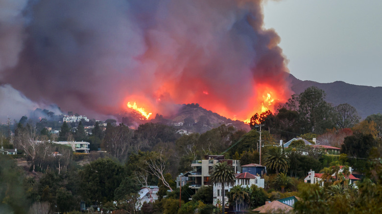 Fire and smoke from a wildfire covering California hillside near several houses