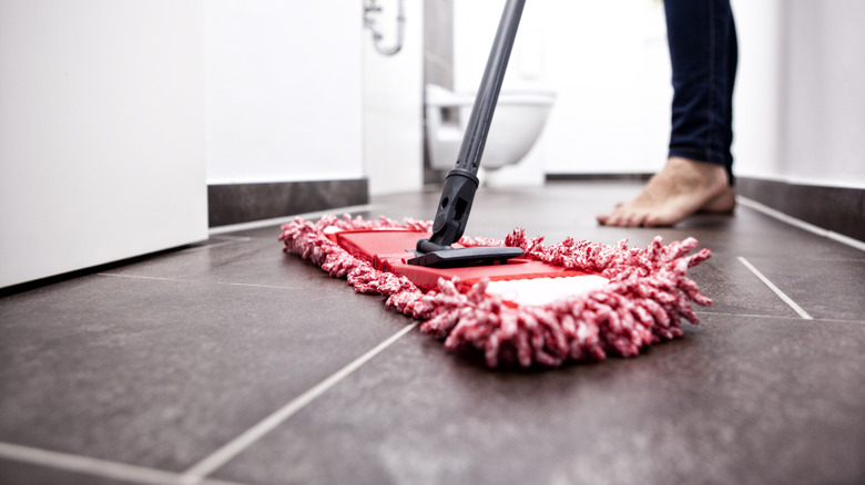 Person cleaning tile floor with a red mop