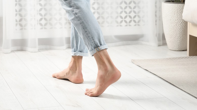 A person is walking on a white wood flooring.