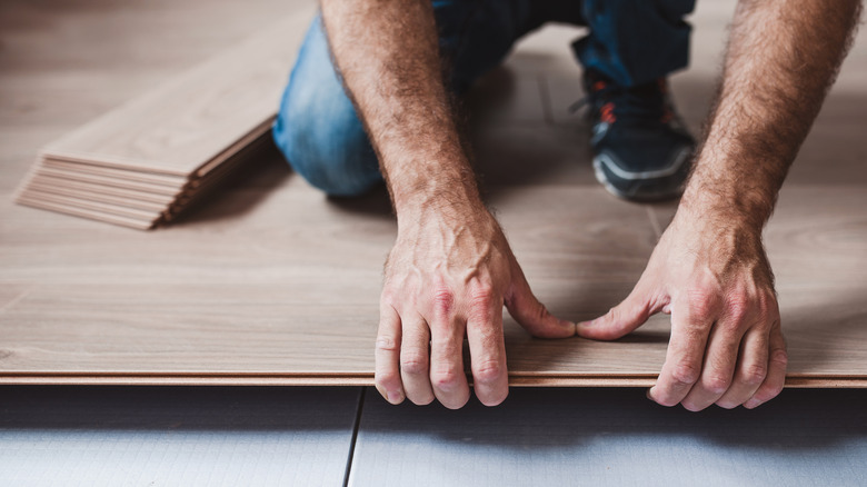 A person is installing a wood plank floating floor.