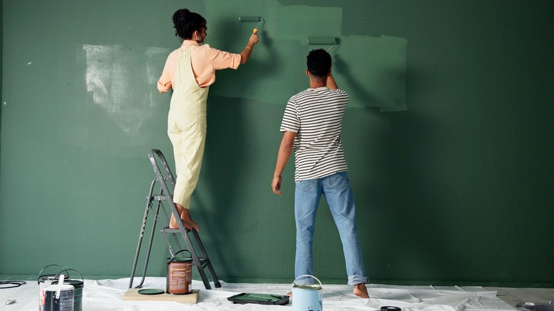 A couple painting their walls green