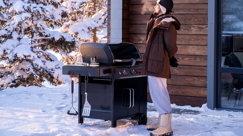 Man grills on snowy patio in winter