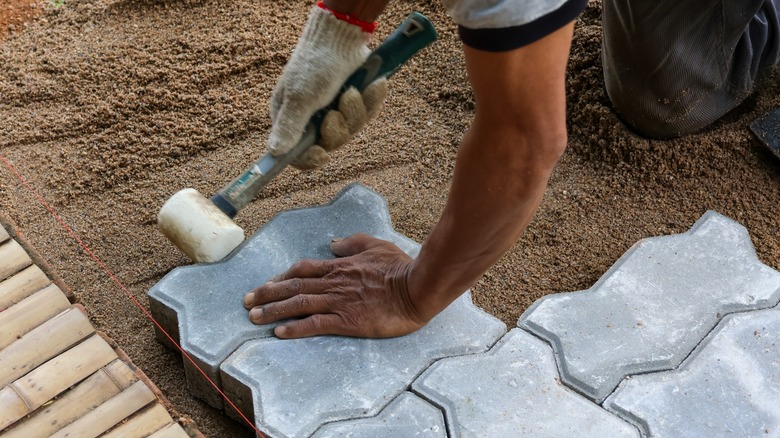 Person laying pavers over dirt