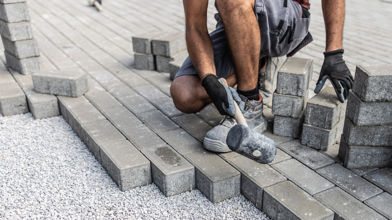 Man laying paver stones over gravel