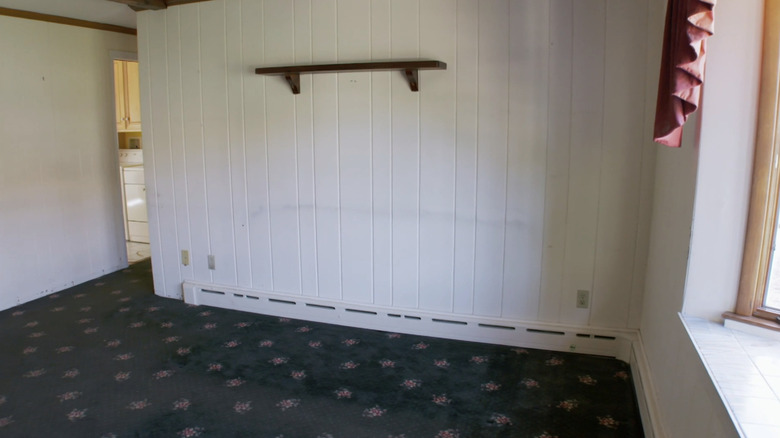 A dated white living room with patterned carpet