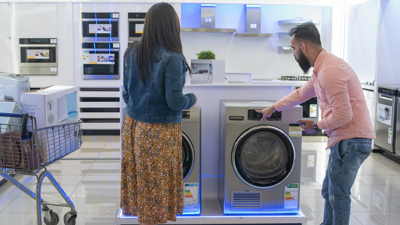 Couple standing in front of washer and dryer in a store