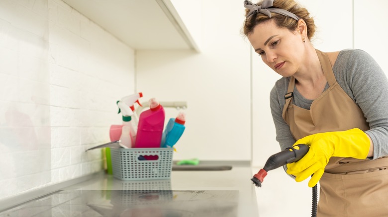 Woman using a steamer to clean the stove