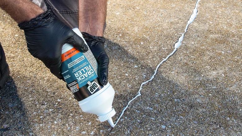 A personal applying DAP Liquid Cement Crack Filler to a crack in concrete