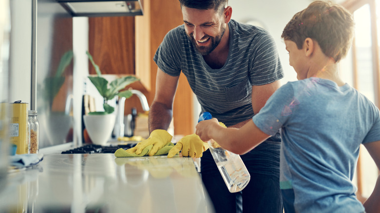 father and son cleaning countertop