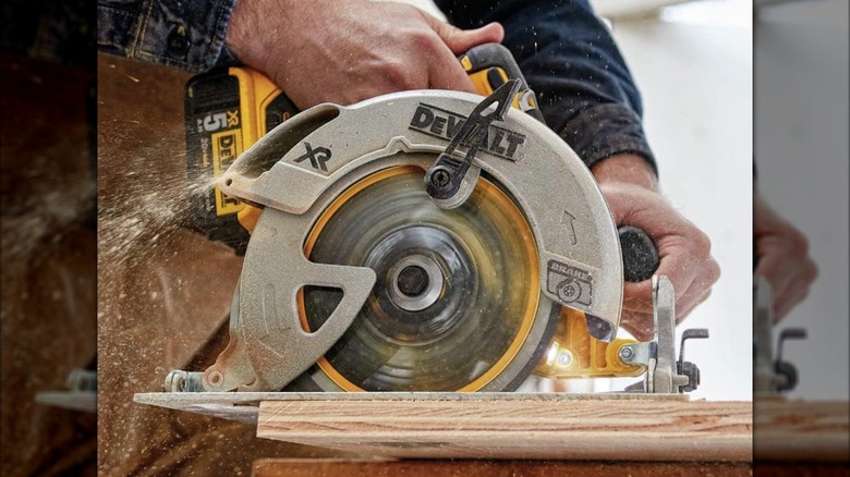 A person cutting wood with a DeWalt circular saw