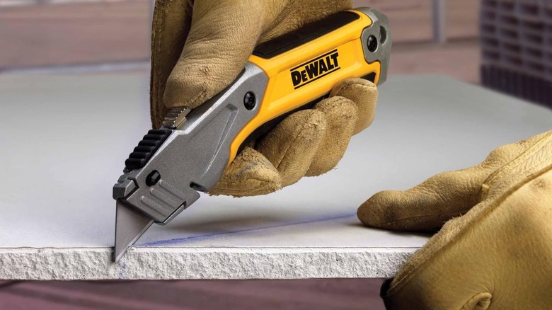 A person cutting tile with a DeWalt utility knife