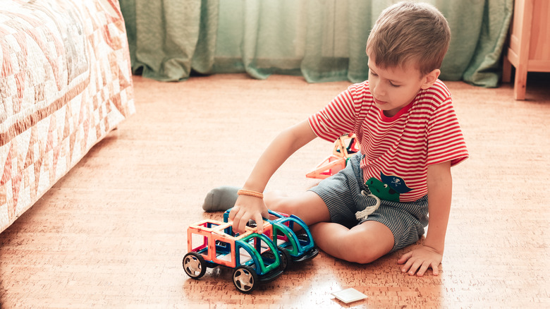 child playing cars on cork flooring