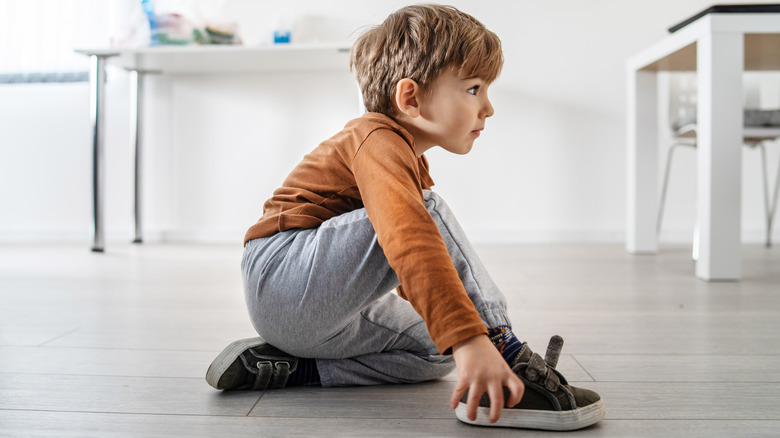 young boy scuffing shoes on laminate wood