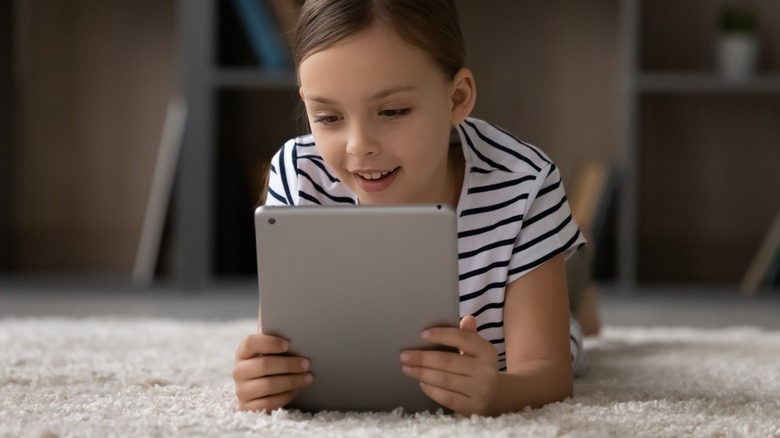 little girl using tablet on carpet