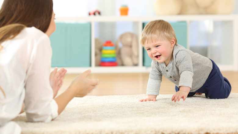 toddler crawling across carpet to mother