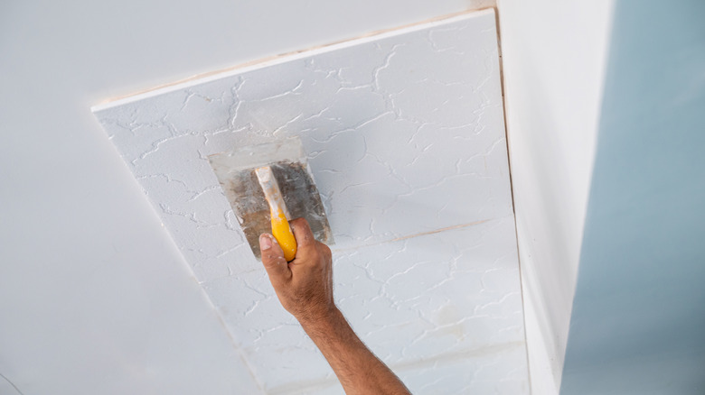 A person installing a tile on the ceiling