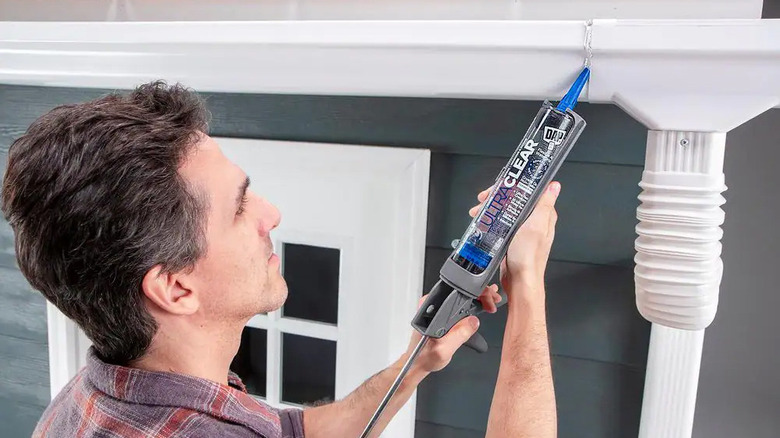 A man uses DAP Ultra Clear Sealant on a white gutter