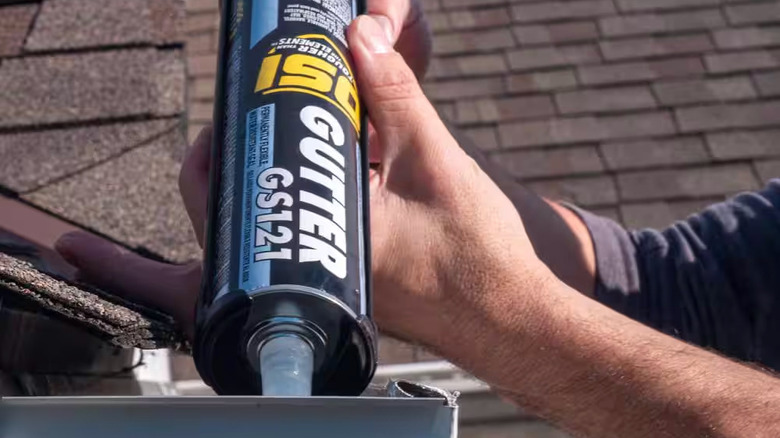 A person applies. OSI Gutter Sealant to a grey gutter