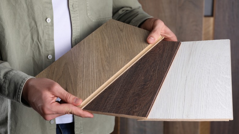 person holding various-colored flooring samples