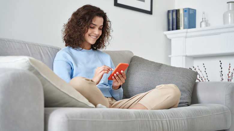 woman using phone on couch