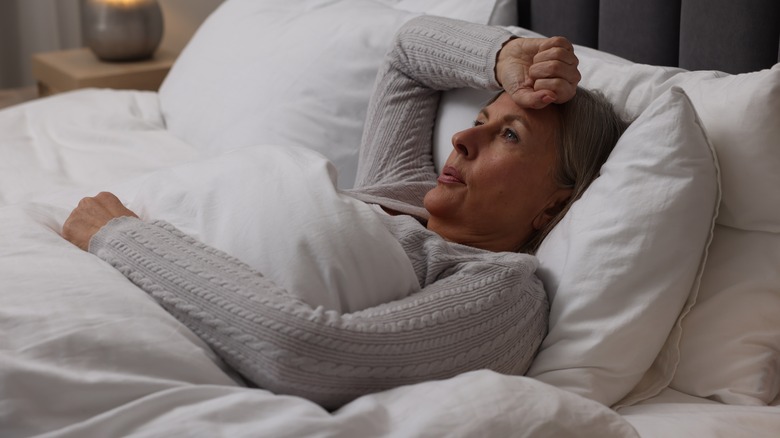 Woman lying in bed with arm over forehead