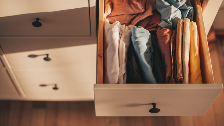 Open light colored drawer with folded colorful shirts