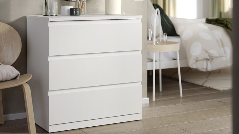 A white STORKLINTA dresser from IKEA in bedroom next to chair