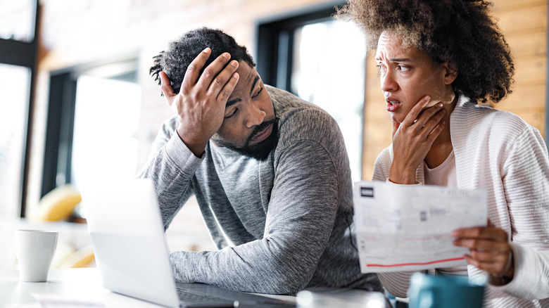 A young couple looks distressed over a bill