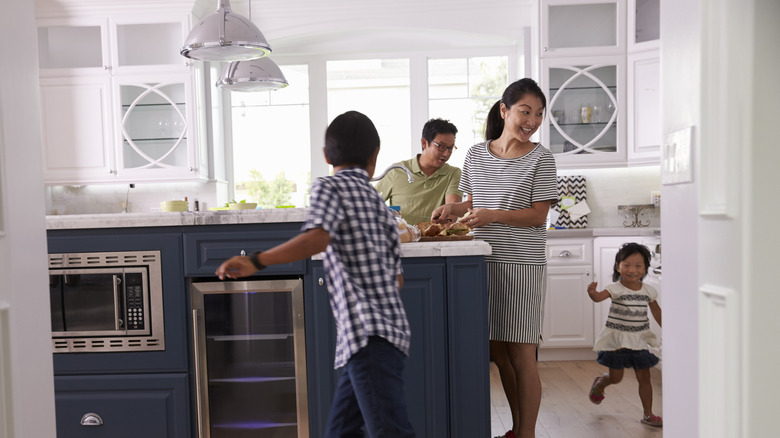 Family in kitchen watching child run around