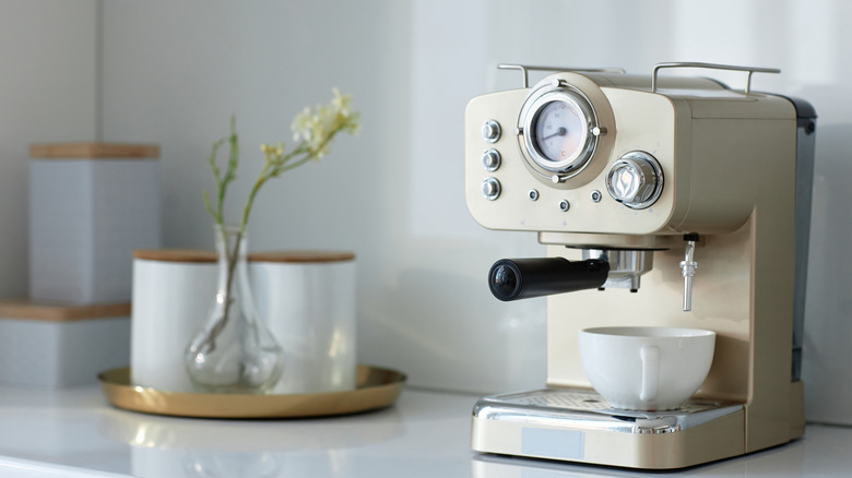 A gold-painted espresso machine sits on a white kitchen counter