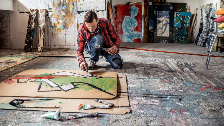 Man painting cardboard lying on floor