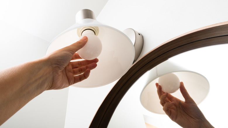 Hand changing lamp in modern bathroom