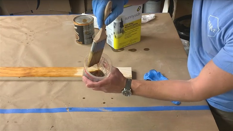 Person soaking paintbrush in mineral spirits