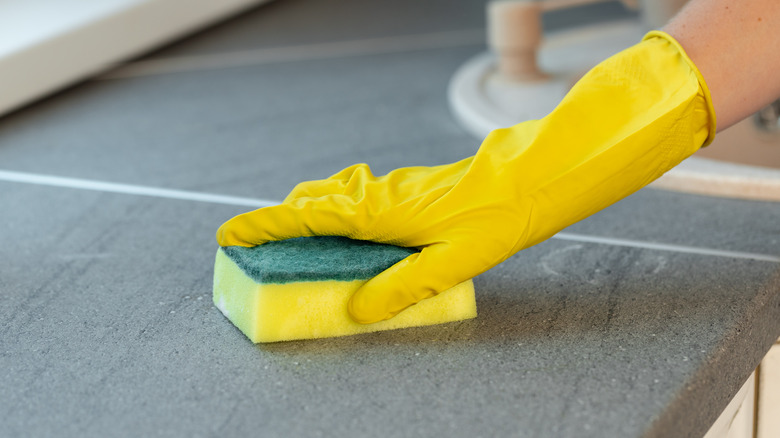 Person cleaning counter with sponge