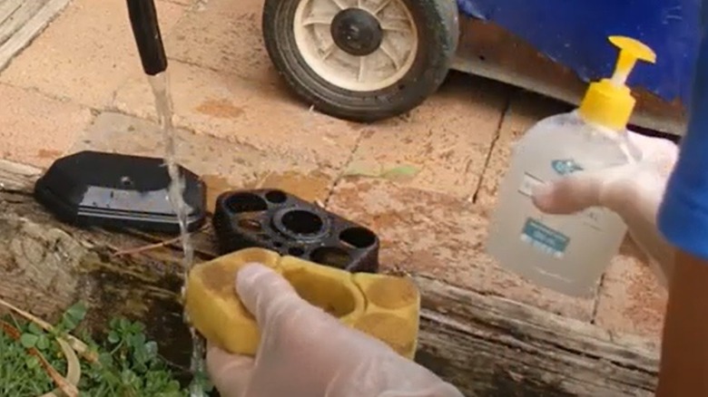 person cleaning lawnmower foam filter