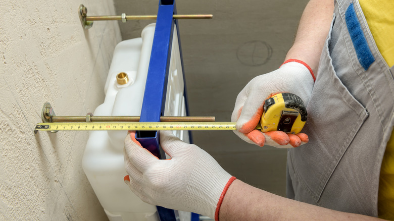 Person measuring around toilet