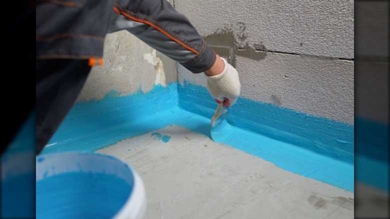 Person painting cinder blocks aqua