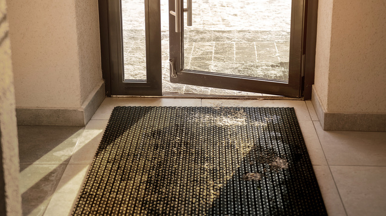 mat in front of open doorway in winter with specks of snow on it