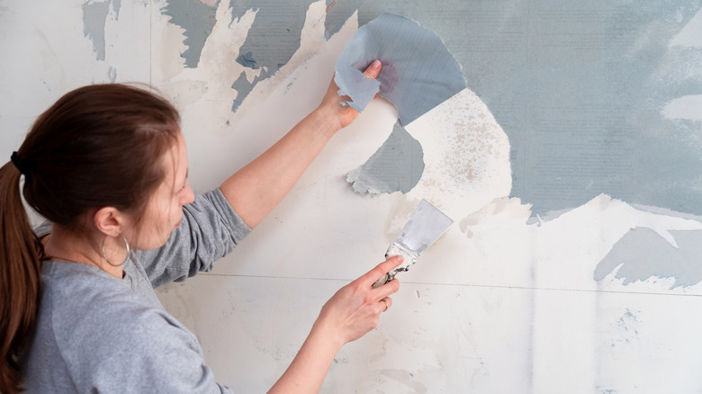 woman removing wallpaper