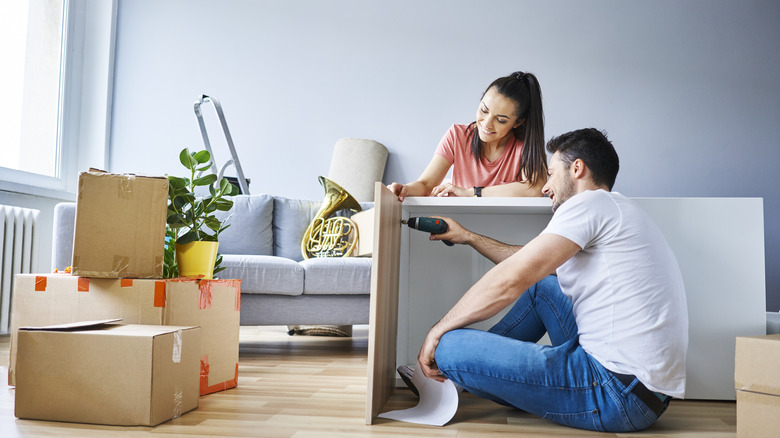 A man and a woman putting together a cabinet in their living room